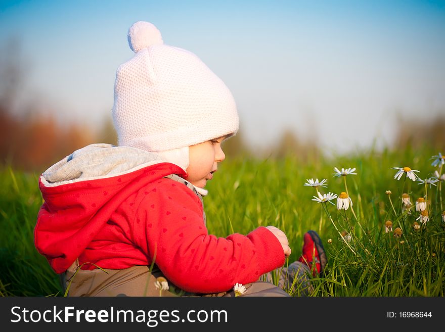 Adorable baby sit on hill and touch flowers