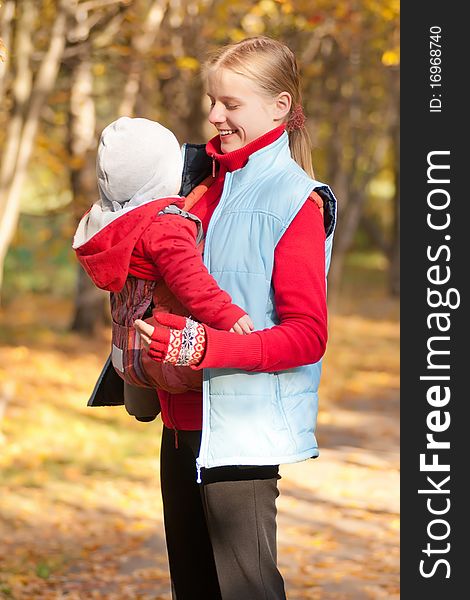 Young adorable mother carry toddler baby in park