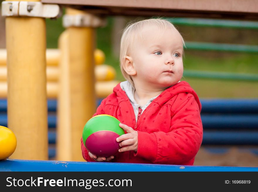 Cute toddler girl play with rubber ball on palyground
