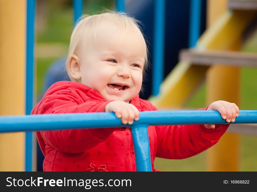 Cheerful Girl Holding The Rails On Playground