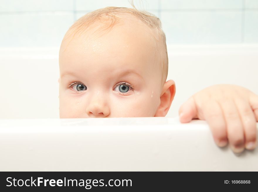 Cute cheerful baby looking from bath hideout