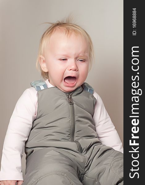 Portrait of crying young baby sit on chair