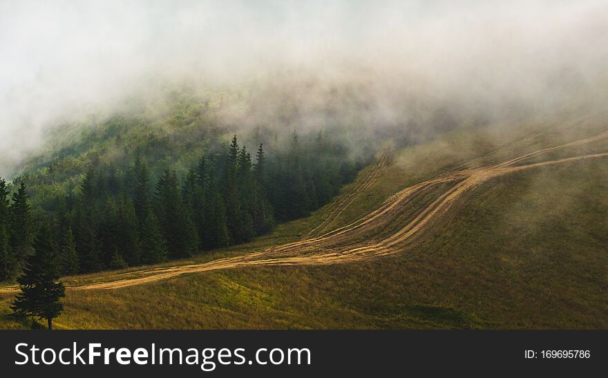 Clouds covered the tops of mountains, a dirt road in the mountains_