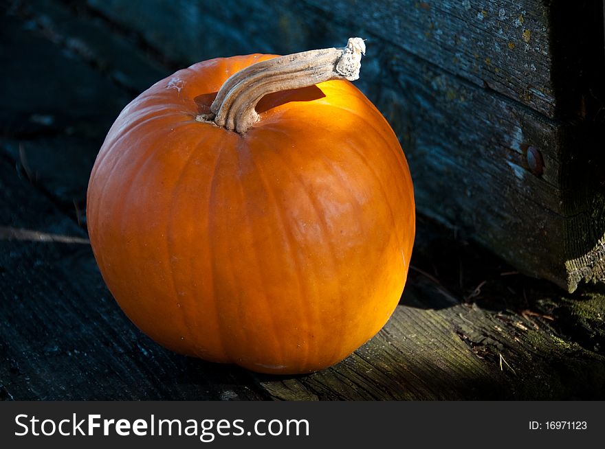 Single orange pumpkin on wooden cart