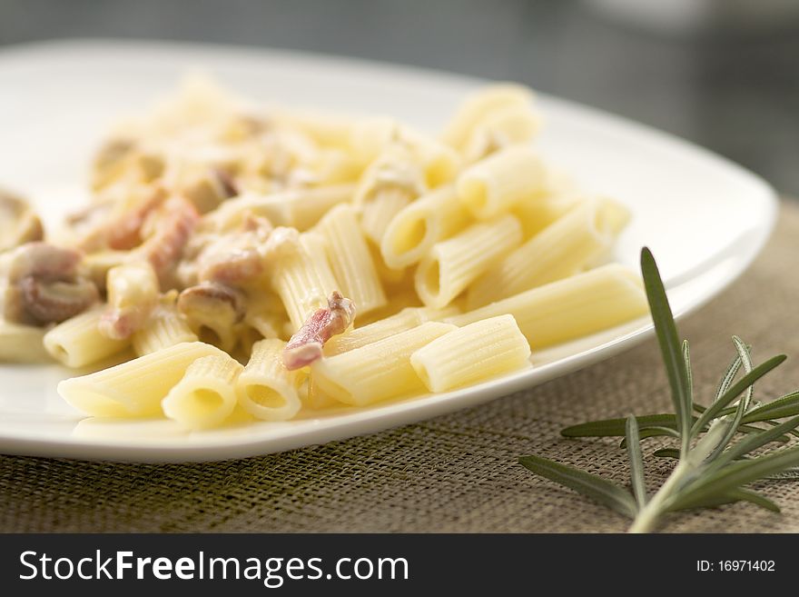 A plate of macaronis with carbonara sauce and bacon. A plate of macaronis with carbonara sauce and bacon