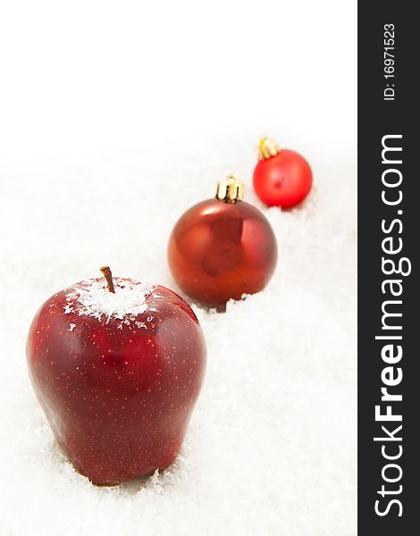 Fresh red apple and red christmas balls on the white snow. Fresh red apple and red christmas balls on the white snow