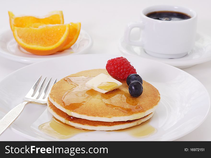 Light and fluffy buttermilk pancakes smothered in maple syrup garnished with a pat of butter and summer berries. Light and fluffy buttermilk pancakes smothered in maple syrup garnished with a pat of butter and summer berries