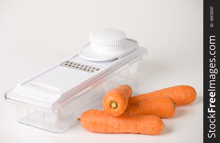 A horizontal image of a food grater and carrots isolated on a white background. A horizontal image of a food grater and carrots isolated on a white background