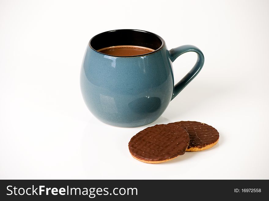 A horizontal image of a mug of hot drinking chocolate and two chocolate biscuits isolated on a plain background. A horizontal image of a mug of hot drinking chocolate and two chocolate biscuits isolated on a plain background