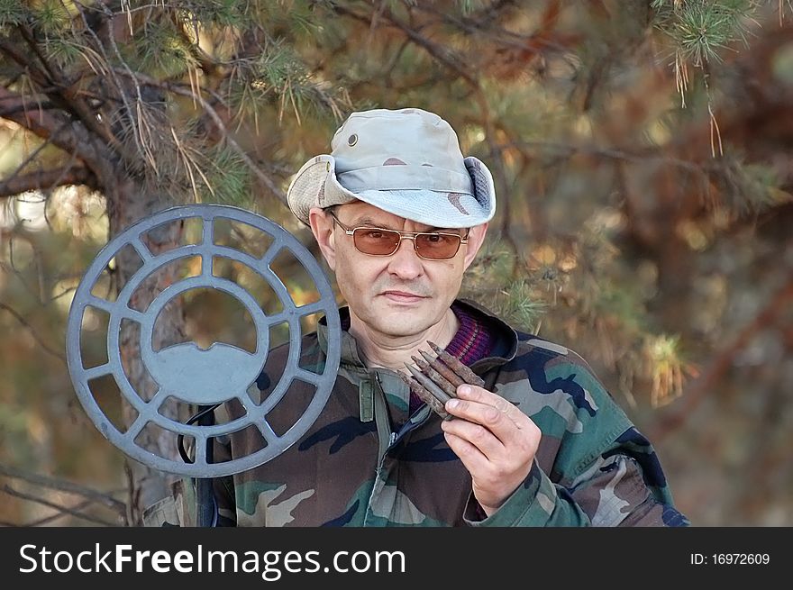 Military archeology. Man with metal detector and excavated German cartridges 7.92 mm caliber on the battlefield of WW2.Ukraine