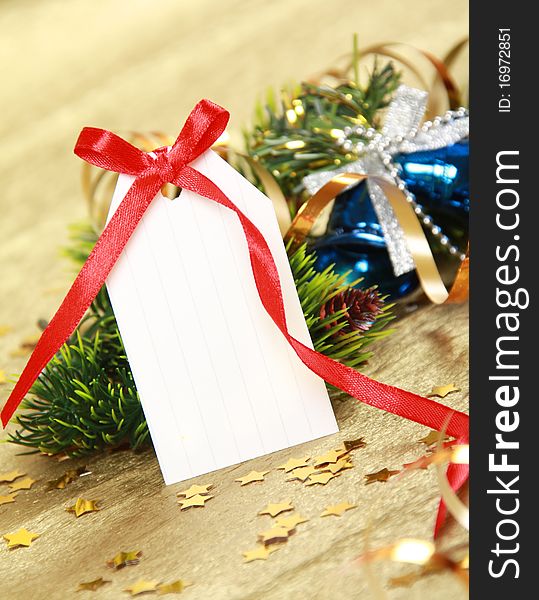 Blank gift tag tied with a bow of red satin ribbon against christmas background