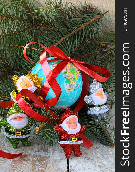 Globe with a gift ribbon and lots of Santa Clauses around. Globe with a gift ribbon and lots of Santa Clauses around