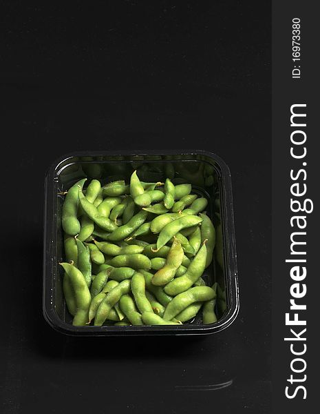 Soybeans in plastic container on black background