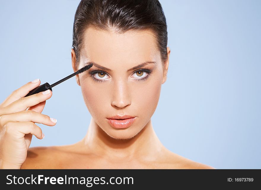Portrait of beautiful woman she is doing makeup, isolated on blue background. Portrait of beautiful woman she is doing makeup, isolated on blue background