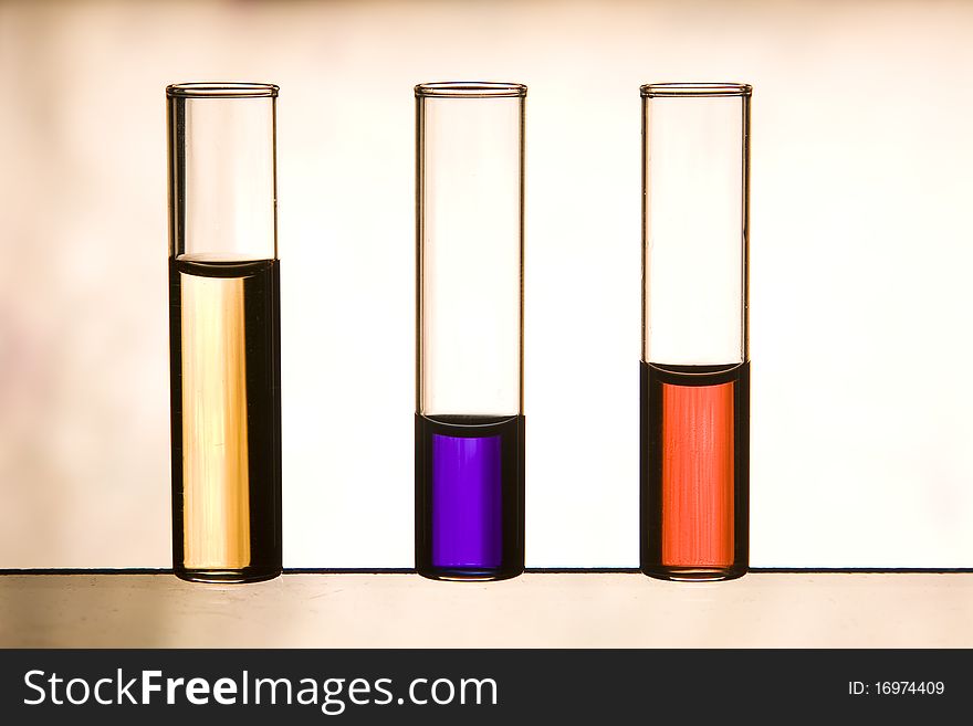 Three vials with red, purple and yellow color liquids in backlight. Three vials with red, purple and yellow color liquids in backlight