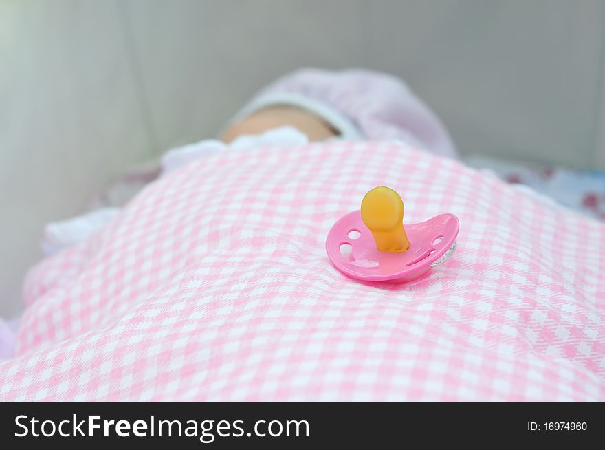 Pink soother on the background of a newborn
