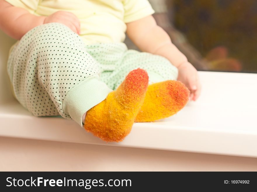 Girl sitting on window sill, legs closeup