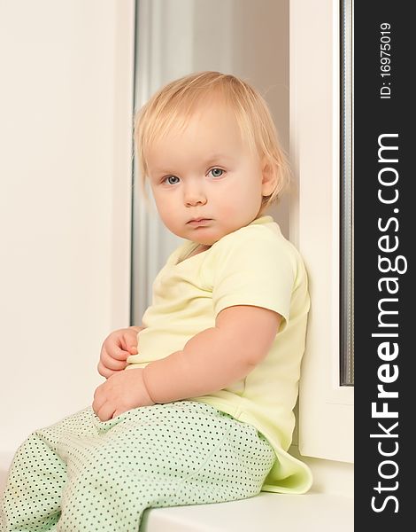 Adorable toddler girl sitting on the window sill