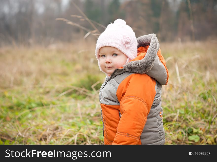 Young cheerful baby stay in autumn field park. Young cheerful baby stay in autumn field park