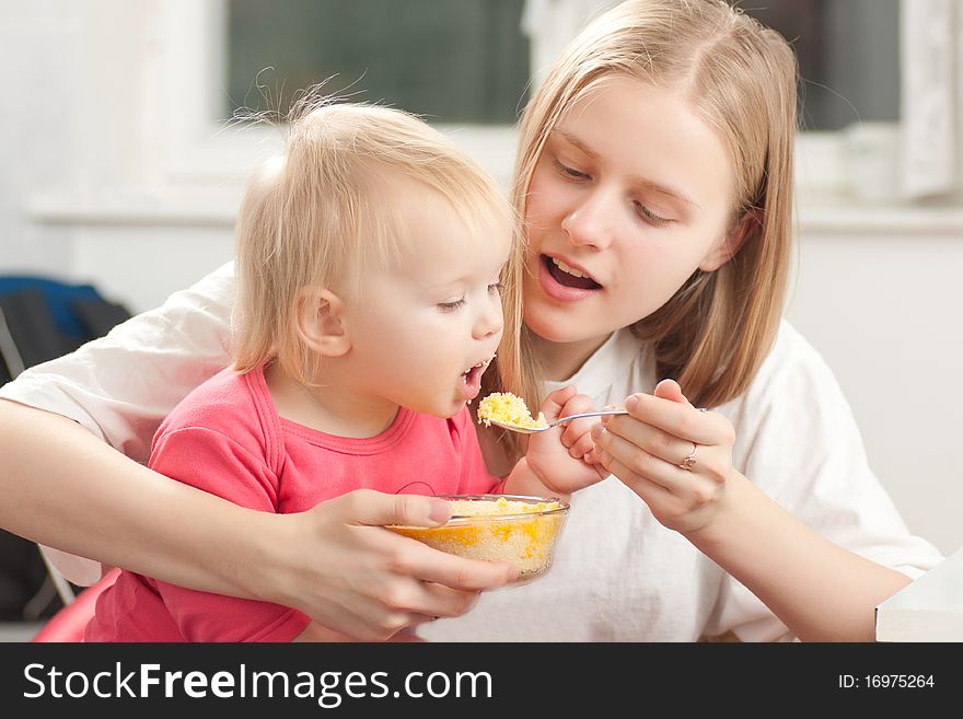 Mother Feeding His Daughter With Porridge