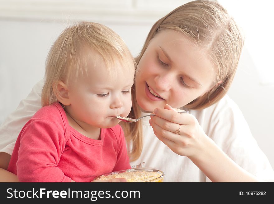 Mother Feeding Daughter With Porridge