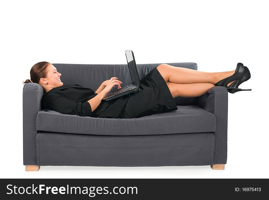 The businesswoman works behind the laptop lying on a sofa at office. The businesswoman works behind the laptop lying on a sofa at office.