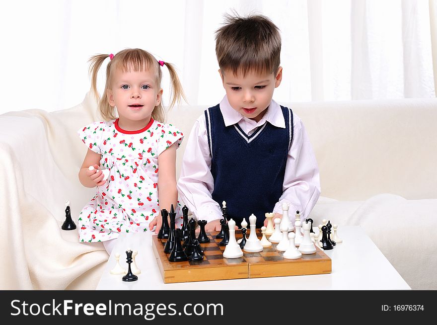 Brother and sister playing chess at a table