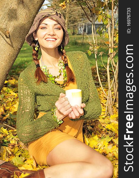 Cute girl holding a mug with a hot drink at fall. Cute girl holding a mug with a hot drink at fall