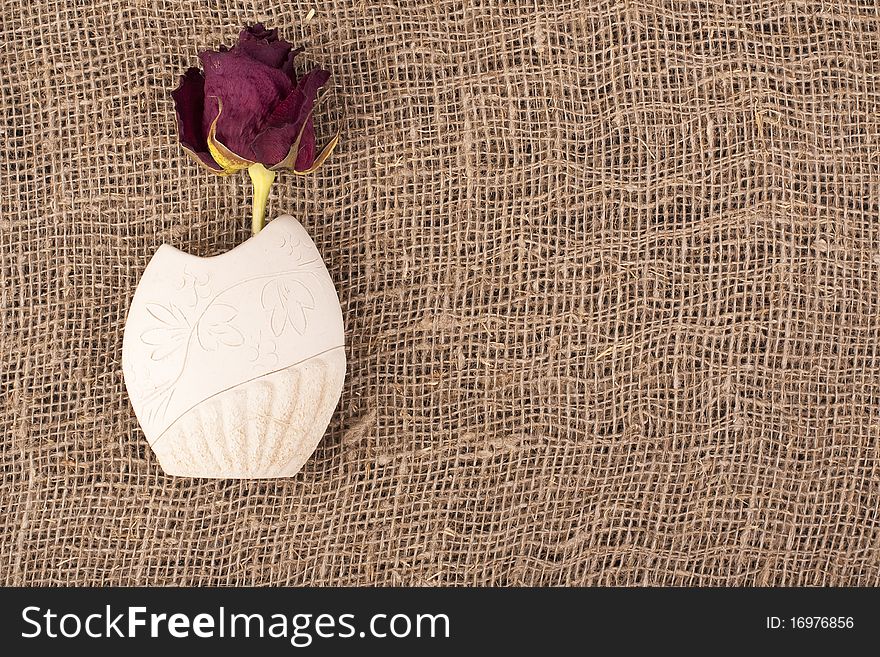 Withering rose in a crock on rough material