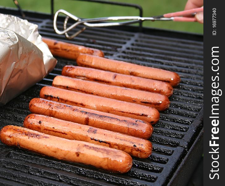 Hotdogs cooking on the grill in the summer time. Hotdogs cooking on the grill in the summer time.