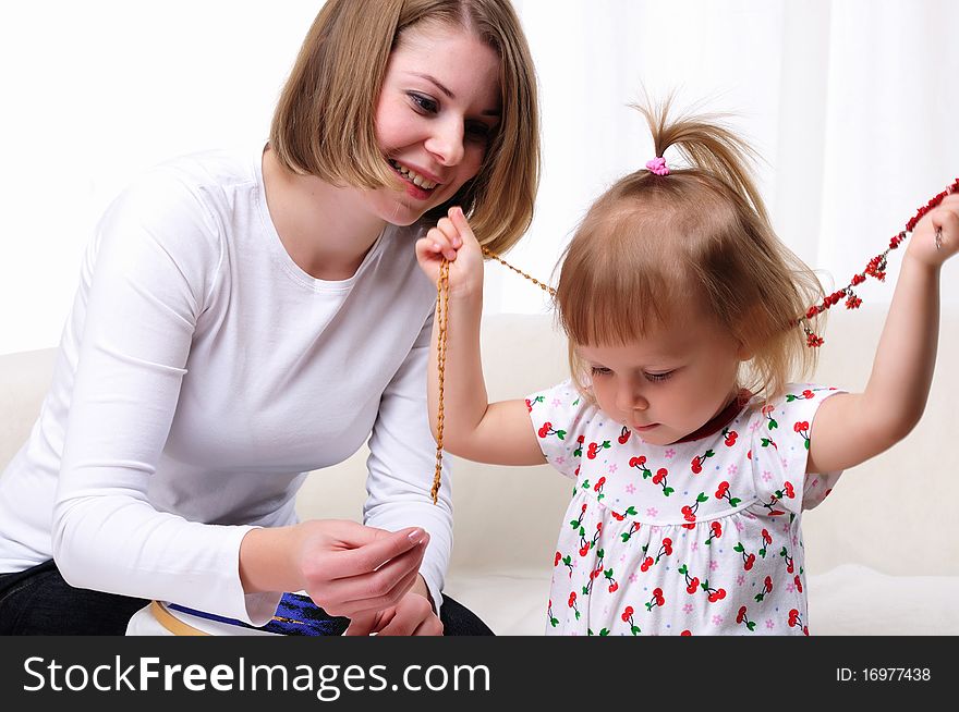 Young mother and her baby daughter spending time together. Dress up in costume jewelry.