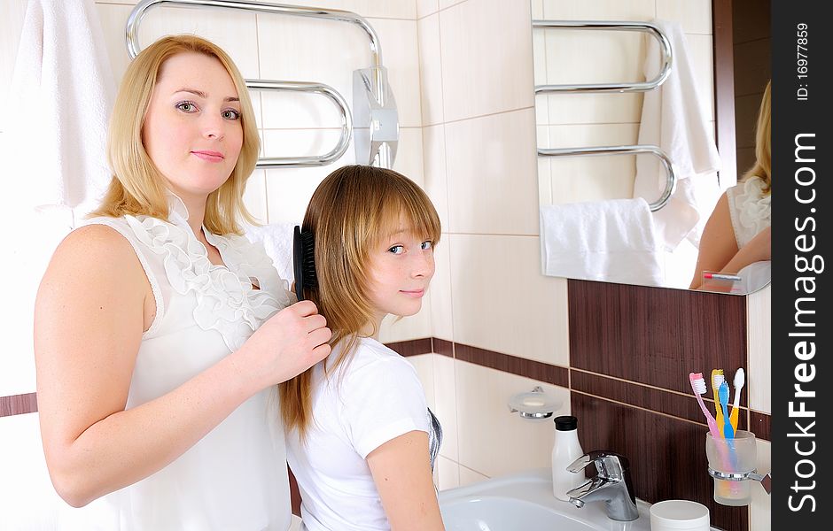 A young girl and her mother take care of the hair in his bathroom