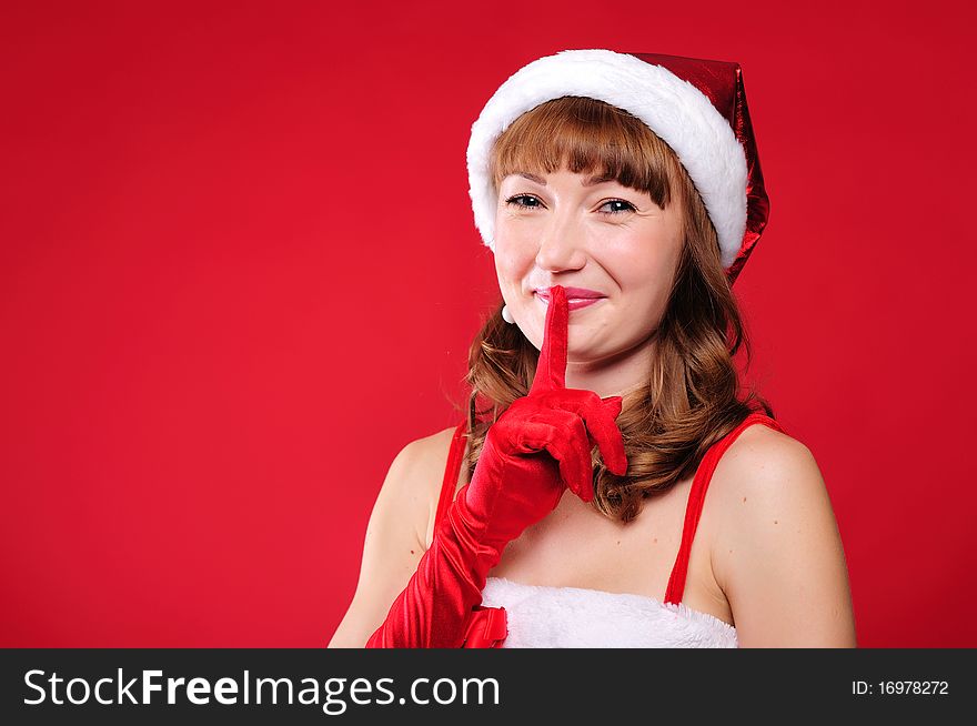 Portrait of a young girl dressed as Santa Claus on a red background. Happy New Year and Merry Christmas!