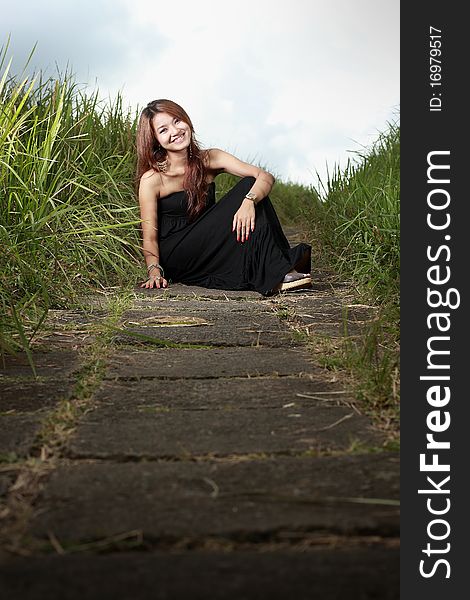 Young beautiful woman smiling outdoors in the meadow using black dress. Young beautiful woman smiling outdoors in the meadow using black dress