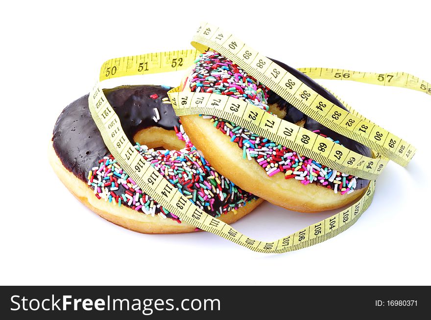 A chocolate frosted donut with colorful sprinkles with a yellow measuring tape wrapped around it. A chocolate frosted donut with colorful sprinkles with a yellow measuring tape wrapped around it