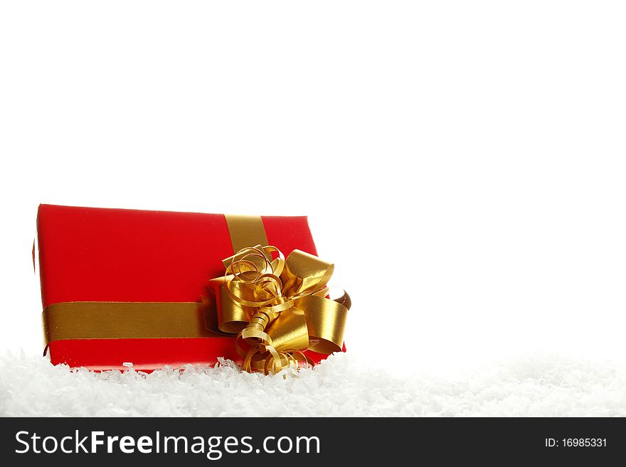 Red gift box tied golden ribbon lying in the snow. Isolated on a white background. Red gift box tied golden ribbon lying in the snow. Isolated on a white background