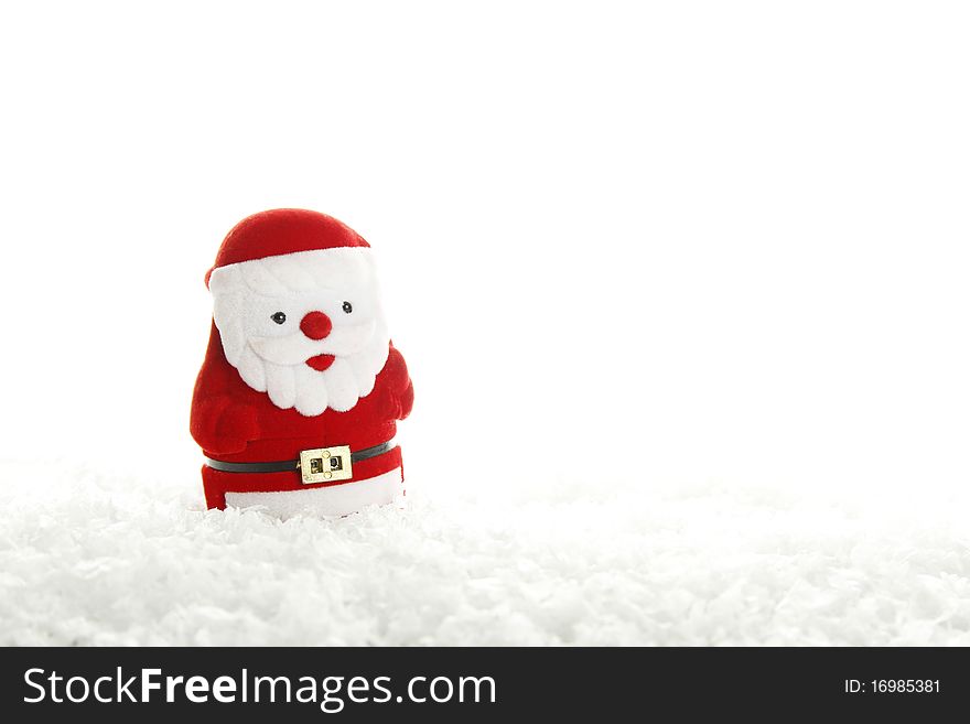 Red Santa Claus figurine stands on an artificial snow. Isolated on a white background. Red Santa Claus figurine stands on an artificial snow. Isolated on a white background