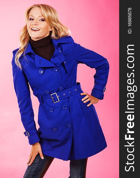 Lovely woman in a blue coat against pink background