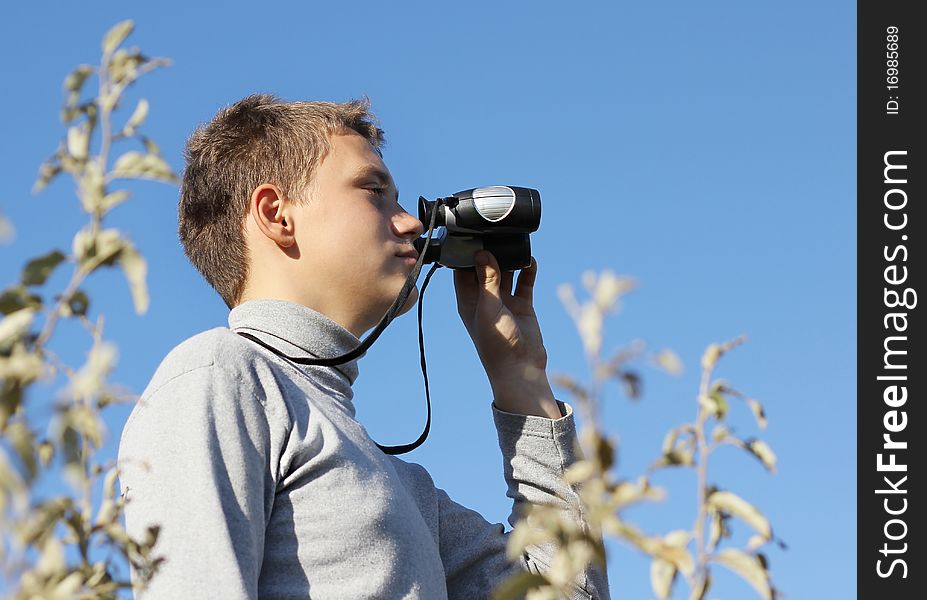 Boy with binoculars in hand in summer day