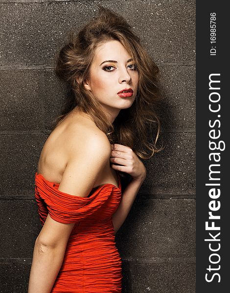 Gorgeous model in a red gown against brick wall background. Gorgeous model in a red gown against brick wall background