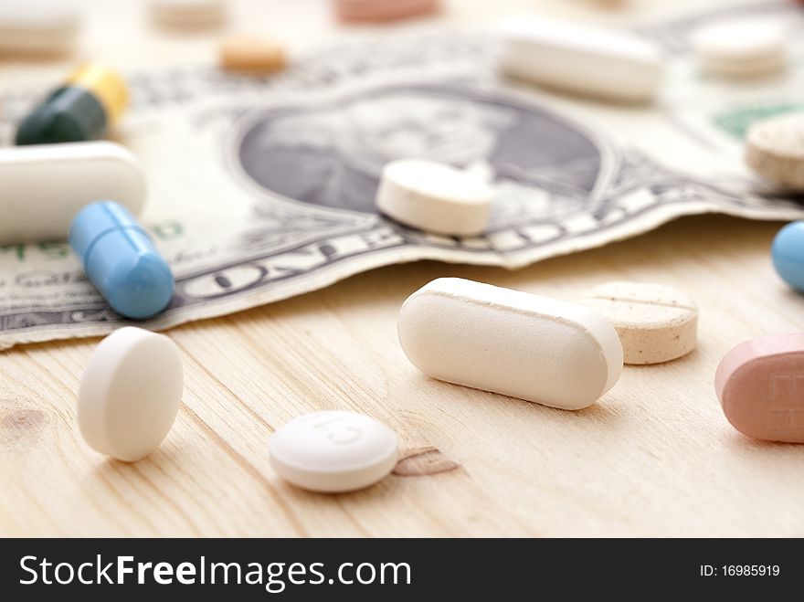 Pills and money on a wooden surface