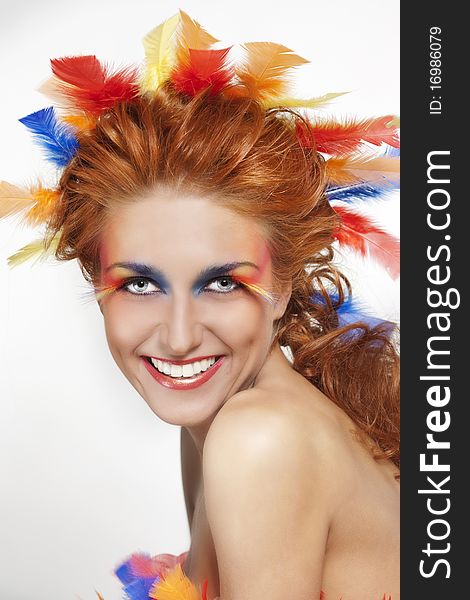 Beautiful woman with face framed in feathers with bright makeup and long faux lashes