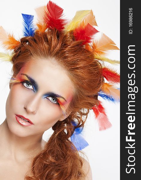 Beautiful woman with face framed in feathers with bright makeup and long faux lashes