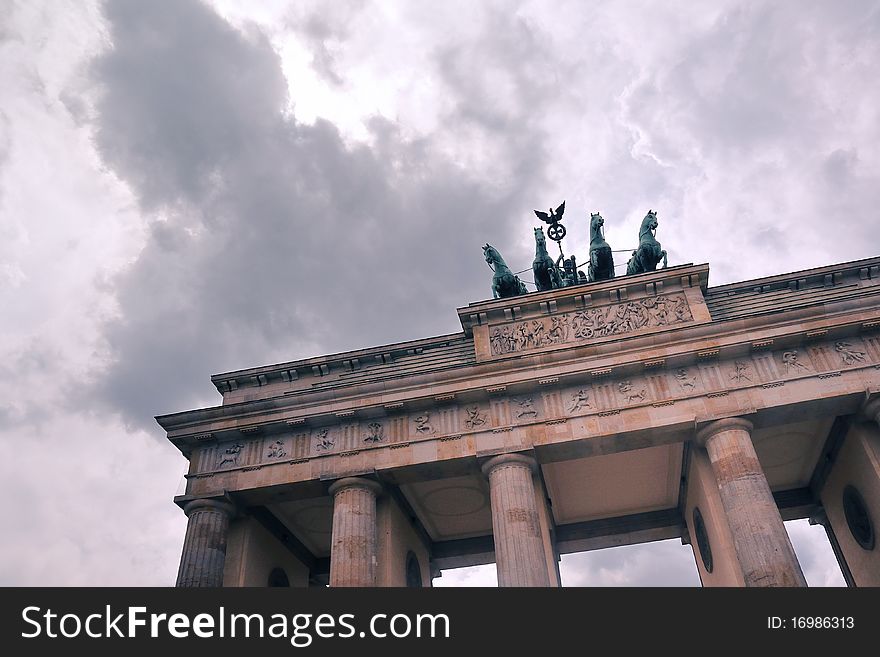 Fragment of famous Brandenburg Gate in  Berlin under dramatic cloudy sky. Fragment of famous Brandenburg Gate in  Berlin under dramatic cloudy sky