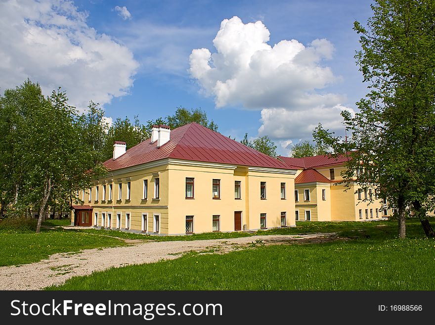 Two-story houses in the park among the trees against the sky.