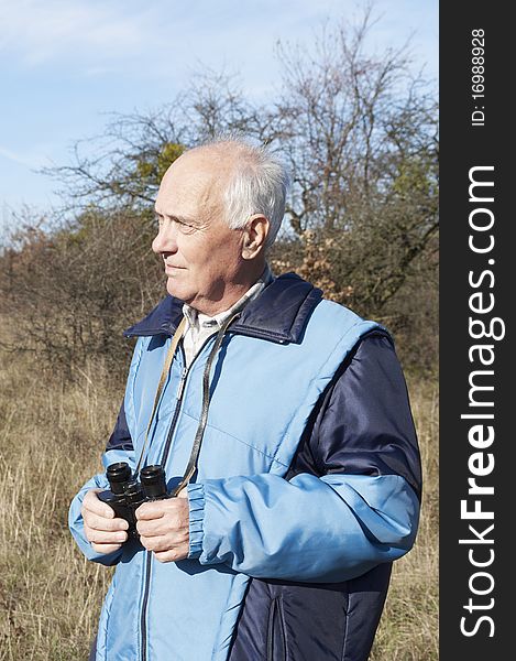 Senior man with binoculars in the nature in Autumn. Senior man with binoculars in the nature in Autumn