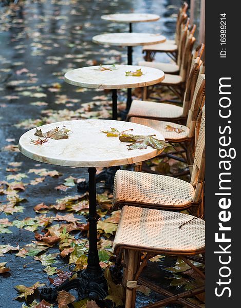 Lonely chairs of a parisian bistro covered by leaf in autumn. Lonely chairs of a parisian bistro covered by leaf in autumn