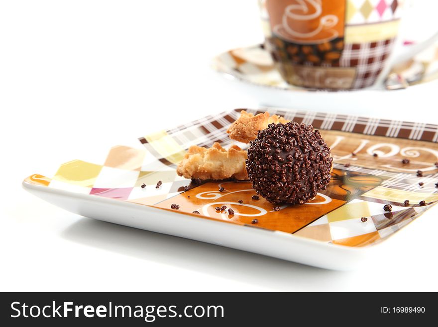 A chocolate praline on a plate with a piece of cookie. A chocolate praline on a plate with a piece of cookie