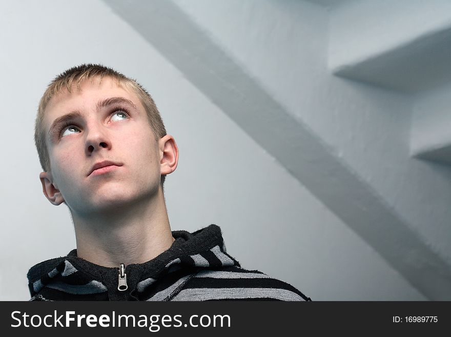 Portrait of young guy standing on gray background with staircase. No glamour, natural. Portrait of young guy standing on gray background with staircase. No glamour, natural