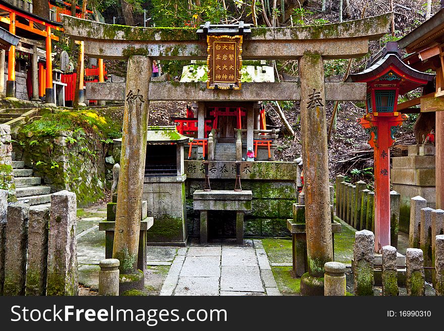 A stone torii gate and shrine at an ancient temle in Kyoto Japan